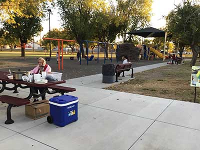 Joyce sitting at picnic table with playground in the background
