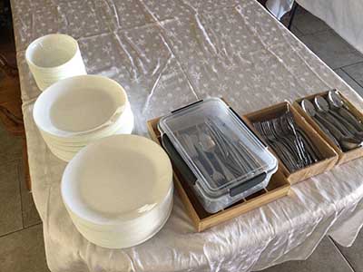plates, bowls, utensils ready for potluck dinner