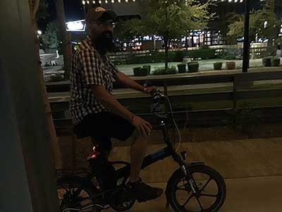 Kush posing while sitting on one of his motorized bicycles