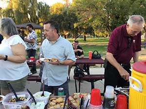 neighbors gather at park for potluck dinner birthday party