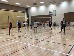 neighbors gather to play indoor volleyball
